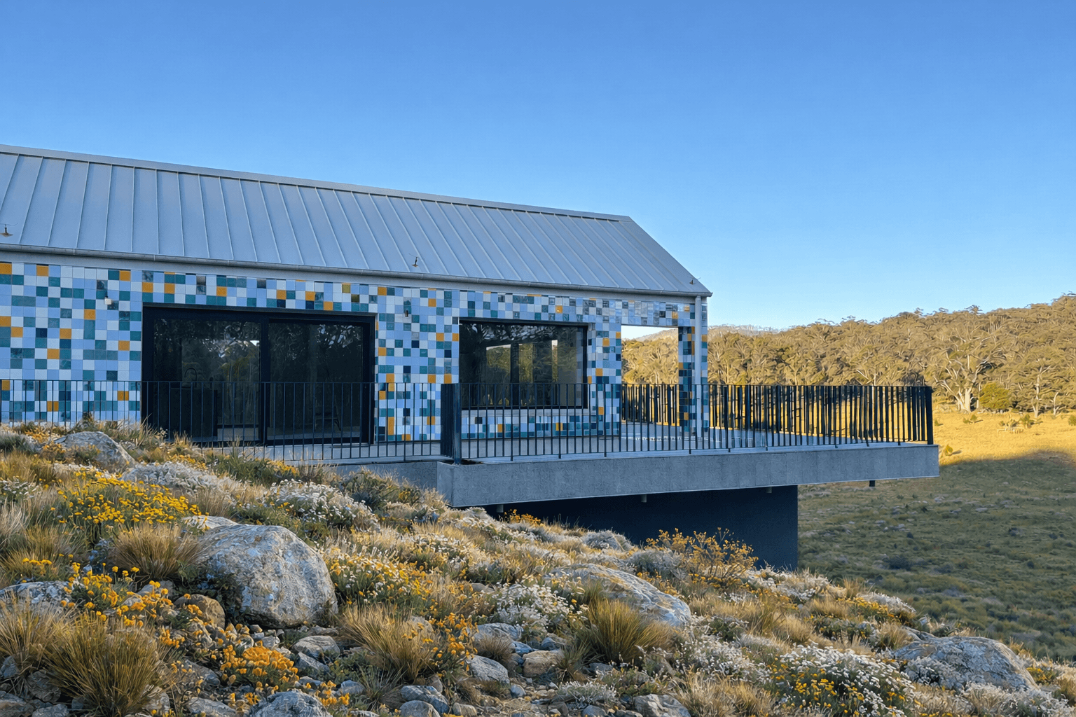 The tiled prefab home on its Budawang ridgeline, wildflowers in the foreground